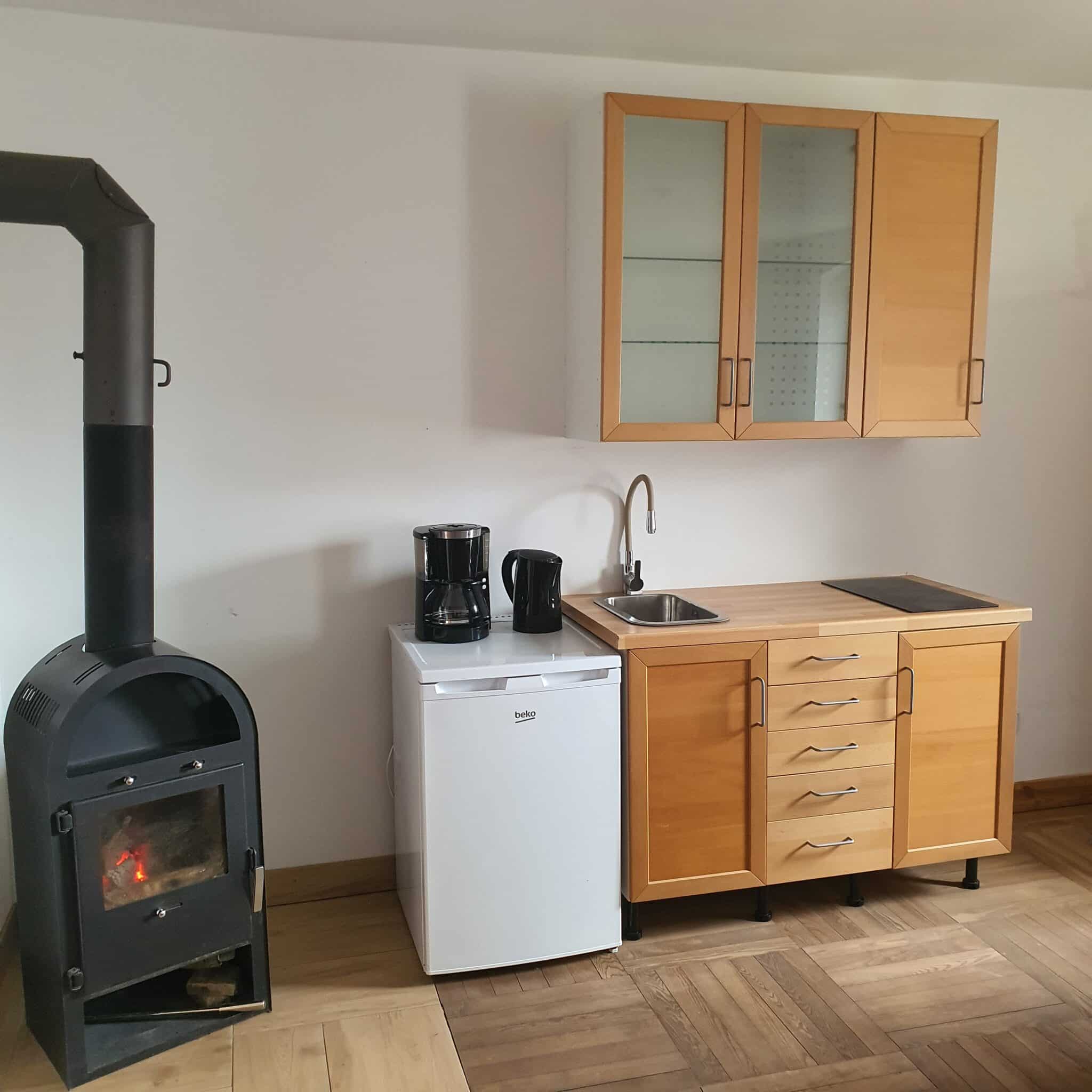 20260326_130641 - Dworek Marmis Küche in der Studiowohnung mit Holzmöbeln, Kühlschrank, Kaffeemaschine und Herd.