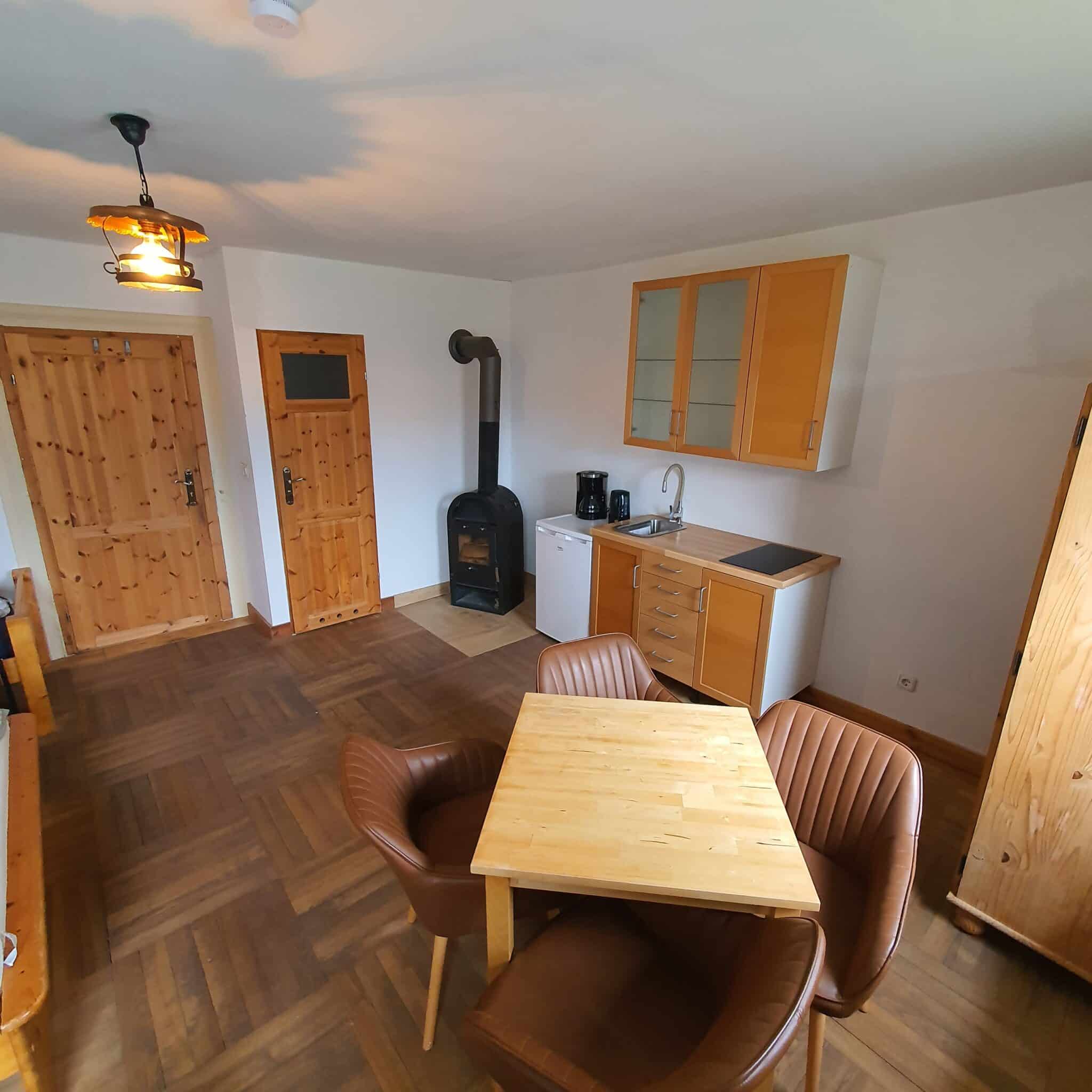 20260326_133951 - Dworek Marmis Moderne Küche in der Studiowohnung mit Holzmöbeln, Tisch und Stühlen.