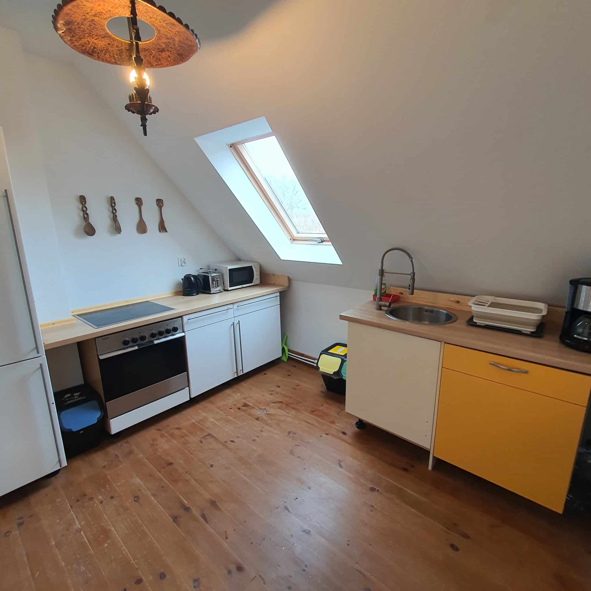 20251206_111652 - Dworek Marmis Gästeküche mit Oberlicht, weißen Möbeln und gelben Schränken, ausgestattet mit Geräten.